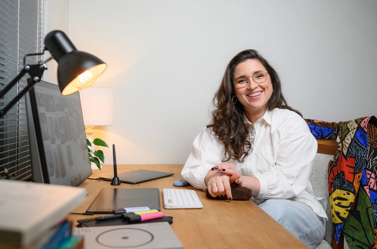 Júlia Wolf Cruz sentada à mesa de trabalho em seu escritório